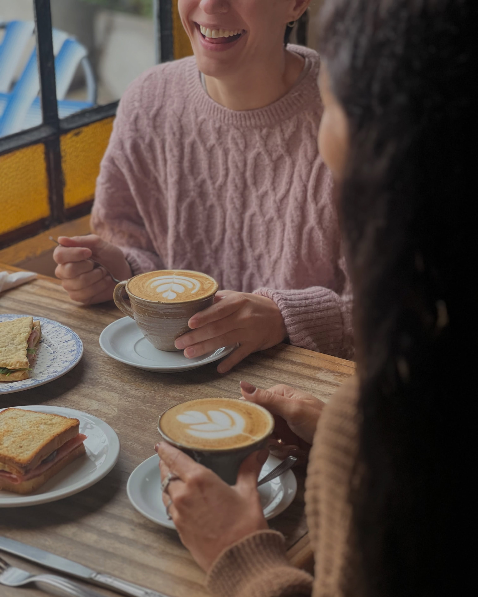 Dos cafés con leche y sándwiches sobre una mesa de madera